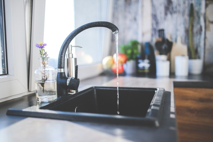 pouring water into glass on kitchen counter